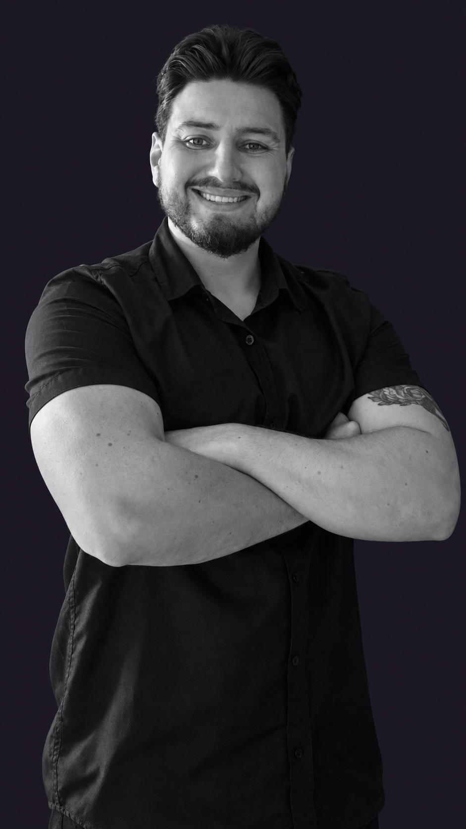 Retrato em preto e branco de Wesley Berton sorrindo, de camisa de manga curta e braços cruzados